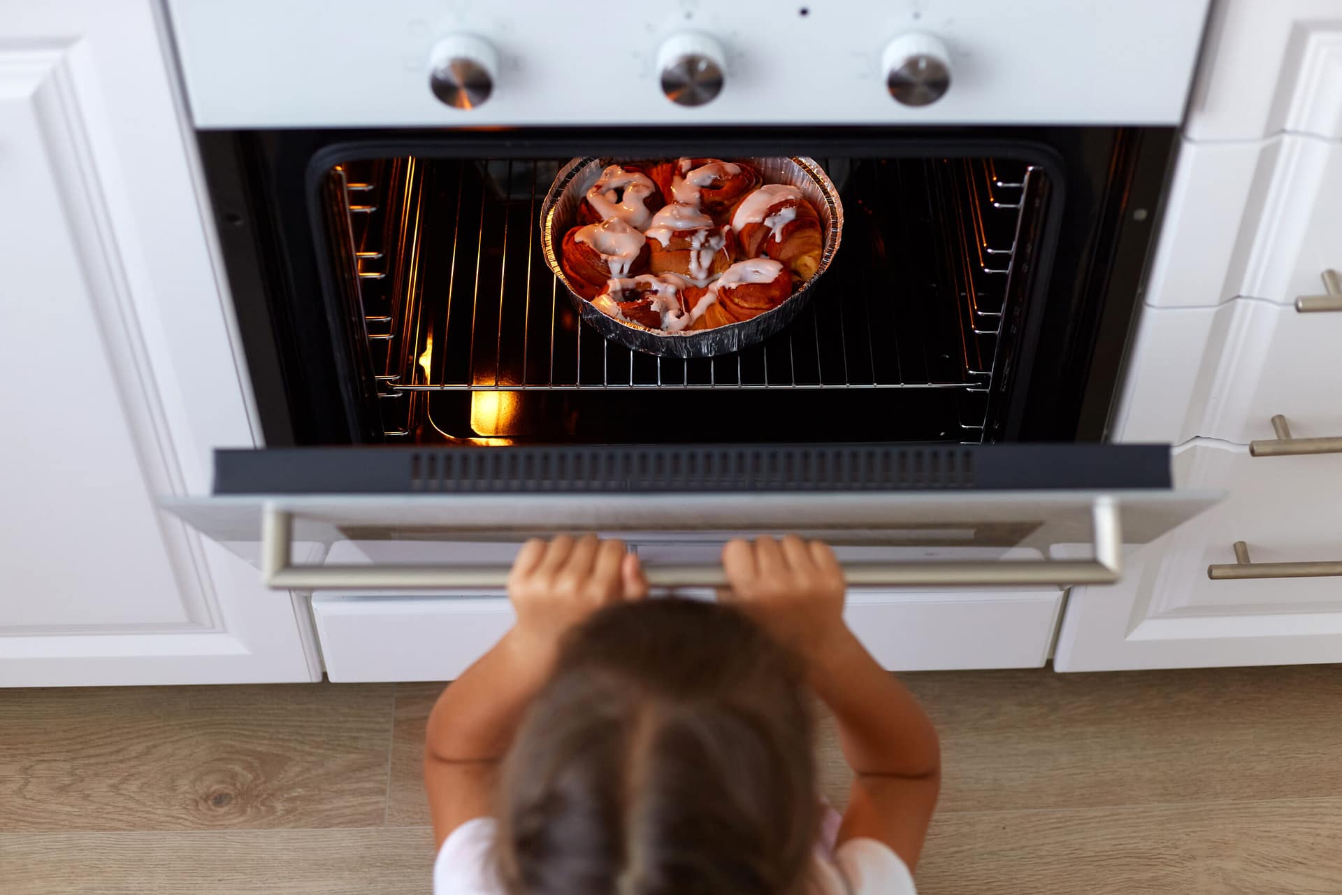 Top view of girl child opening oven looking at tasty croissant or other baking n the oven, cooking process on kitchen, small dark haired female kid wants delicious sweets. Reliable 24/7 Home Appliance Repair Services Near Me
