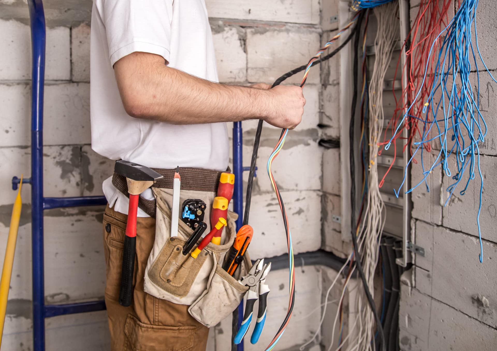 Electrician working near the Board with wires. Installation and connection of electrics. Reliable 24/7 Home Electrical Services Near Me